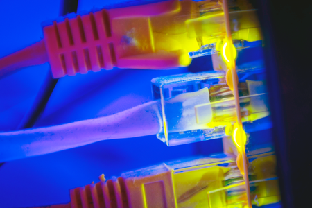 Ethernet calbe wires lighting up connected to an internet router modem are seen against a blue background.