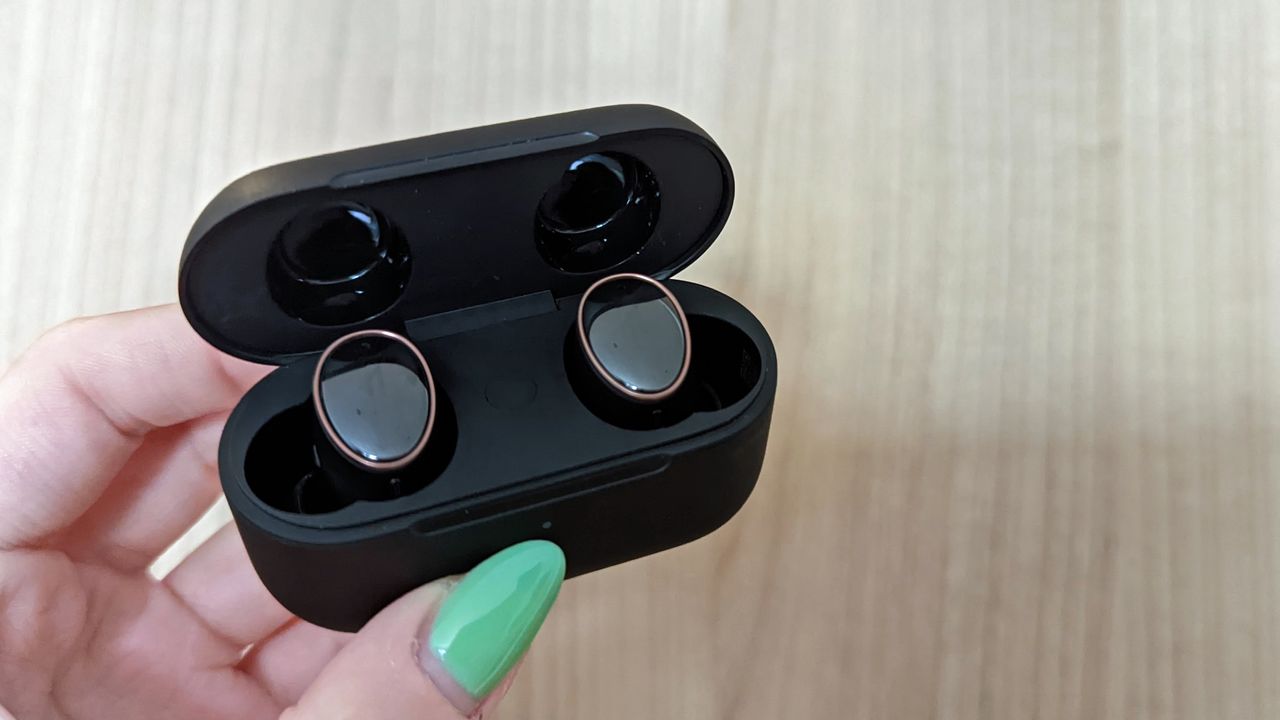 1More Evo review: holding open true wireless earbud case in front of wood