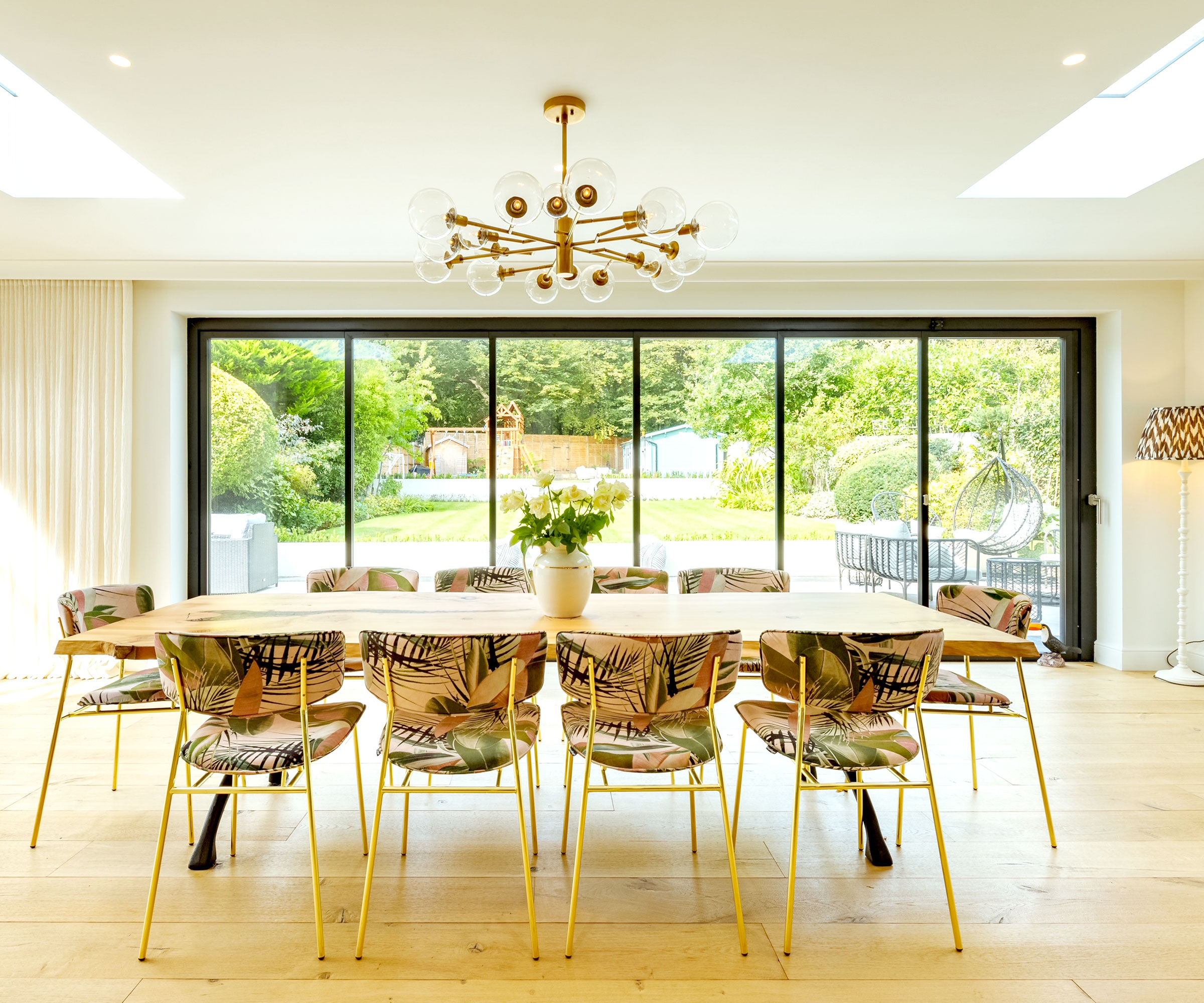 Contemporary table and chairs in a large extension with IDSystems slide and turn doors looking out onto garden
