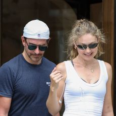 Gigi Hadid with Bradley Cooper in Paris, wearing a white tank top, gray leggings, and brown suede New Balance sneakers