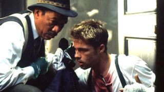 Brad Pitt as David Mills and Morgan Freeman as William Somerset in a police station talking on a black phone during a scene in the movie Seven.