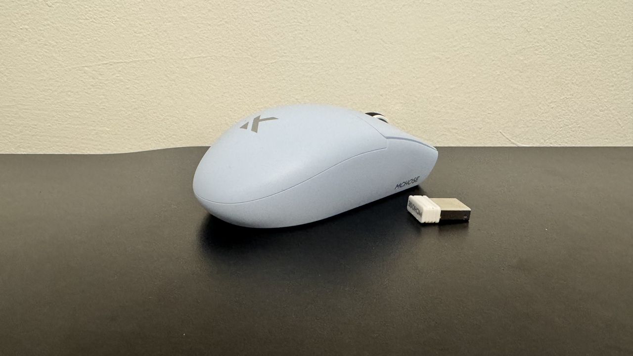 The blue Mchose G3 V2 gaming mouse from the right side with 2.4 GHz connector, on a black desk