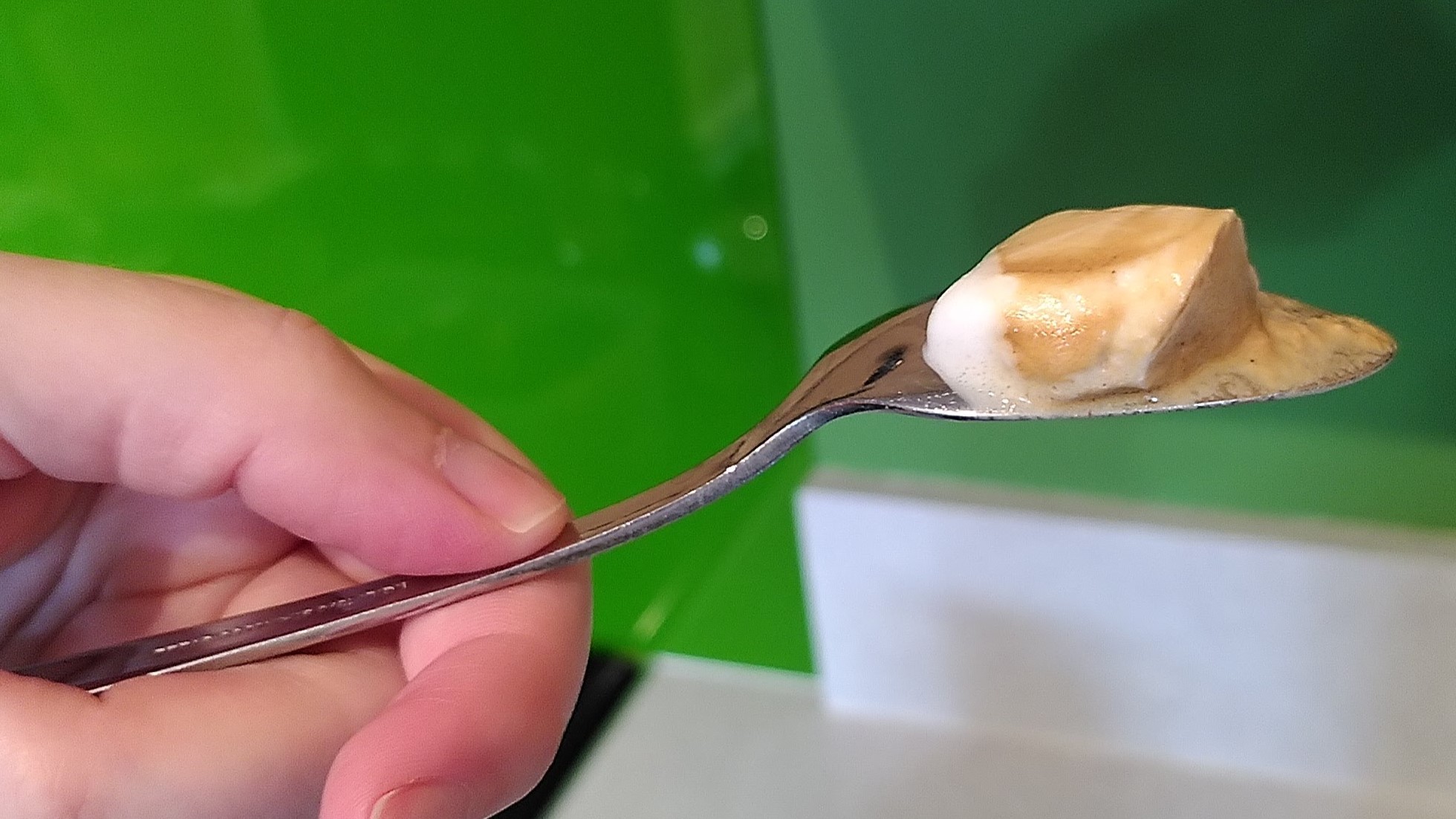 Thickly foamed almond milk sitting on the back of a spoon