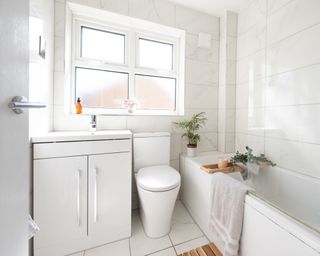 Small white bathroom with sink, toilet, shower and cabinet with drawers below the sink