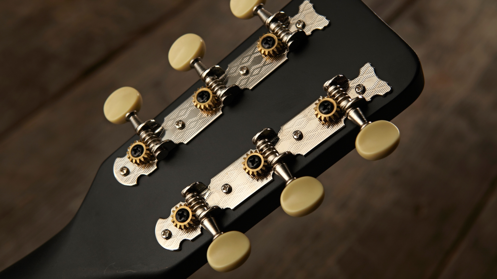 The tuners on the back of a Gretsch acoustic guitar headstock