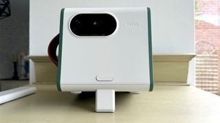 BenQ GS50 home cinema projector angled up showing front foot on wooden surface