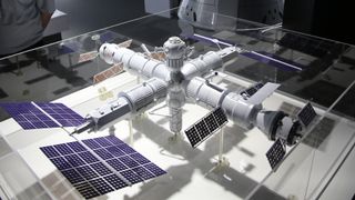 a model of a cross-shaped space station in a glass case in a museum 