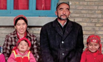 A Muslim Uighur man rests with his two wives and their six children in front of their house at the Buzak Commune. Near Khotan, Xinjiang Province, People's Republic of China. 