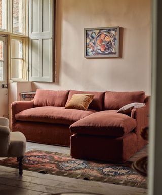 pink painted living room with a red linen sofa and a vintage rug