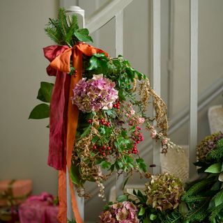 Floral bouquet with pink Christmas roses tied to a white staircase