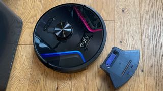The Eufy RoboVac X8 with its dust canister removed on a wooden floor