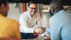 Business professionals shake hands over a signed contract