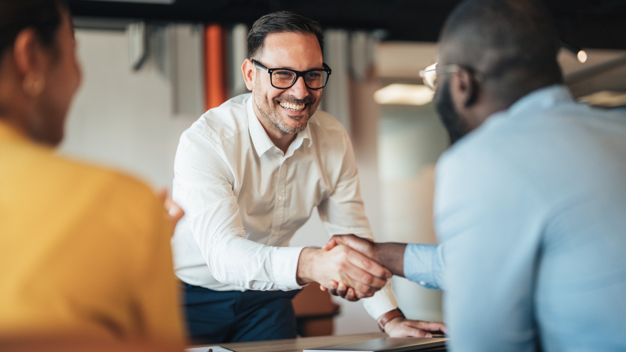 Business professionals shake hands over a signed contract
