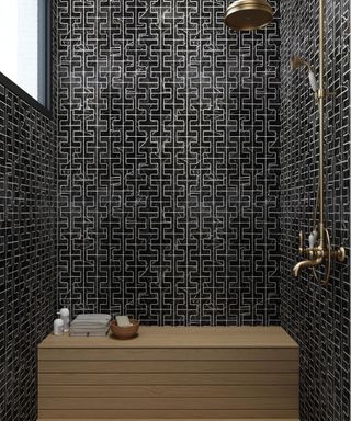 Black wet room with gold fixtures and fittings, wooden shower bench