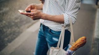 Woman slouching while using her phone and holding bag