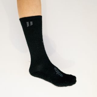 A white leg wears a black cycling sock against a white background