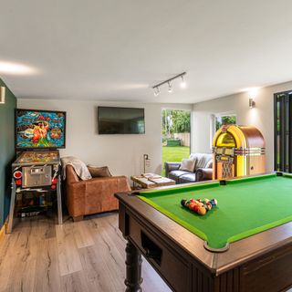 Games room with arcade game, jukebox and pool table inside Green Retreats garden room