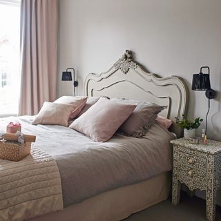 double bed with pink bedding next to patterned bedside table