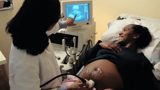 A woman smiles while looking at her ultrasound