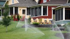 Sprinklers on a lawn in front of suburban houses