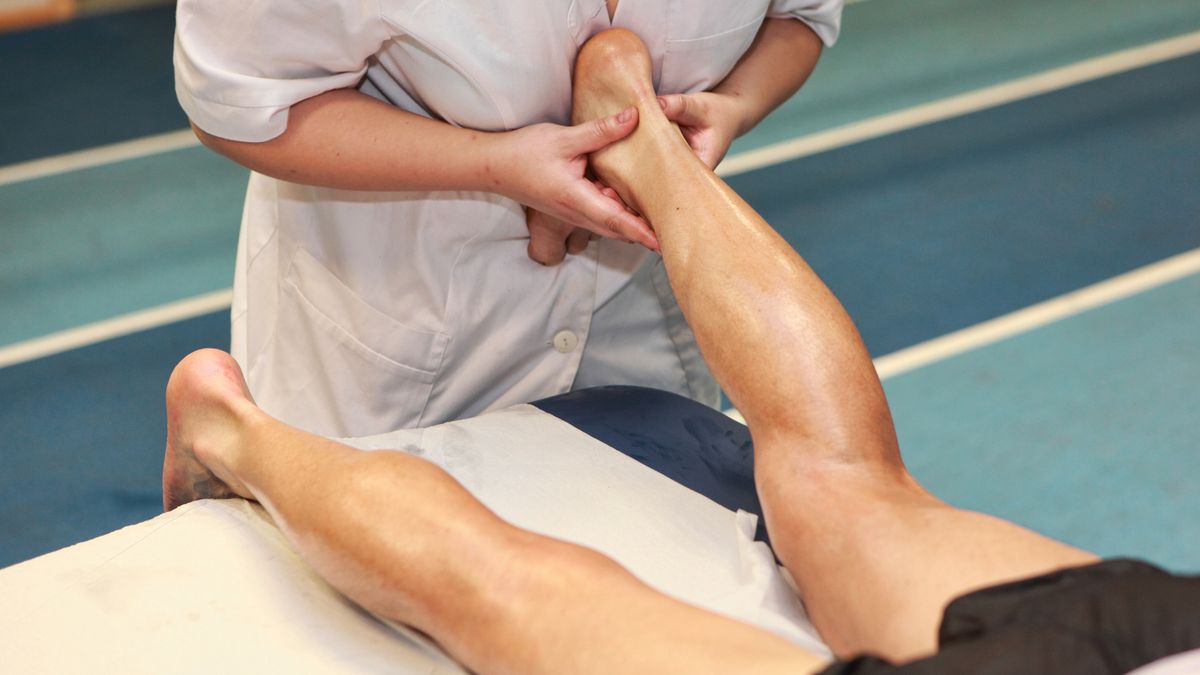 Masseuse massaging athlete’s Achilles tendon