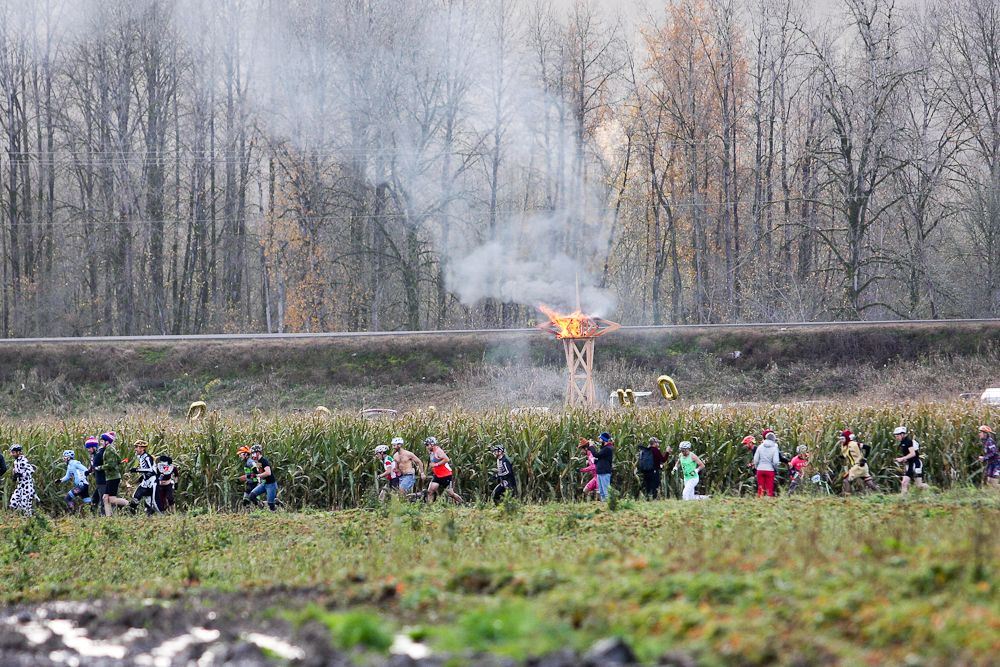 Riders run for their bikes as the wooden structure on fire int he background signals the start of the men's race.