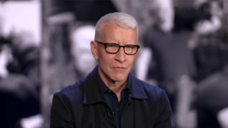 Anderson Cooper wearing glasses and a dark shirt in an interview with 60 Minutes