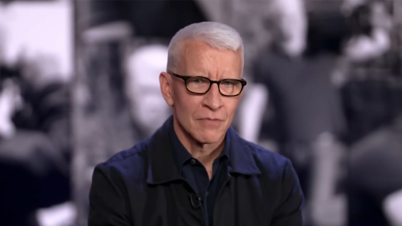 Anderson Cooper wearing glasses and a dark shirt in an interview with 60 Minutes