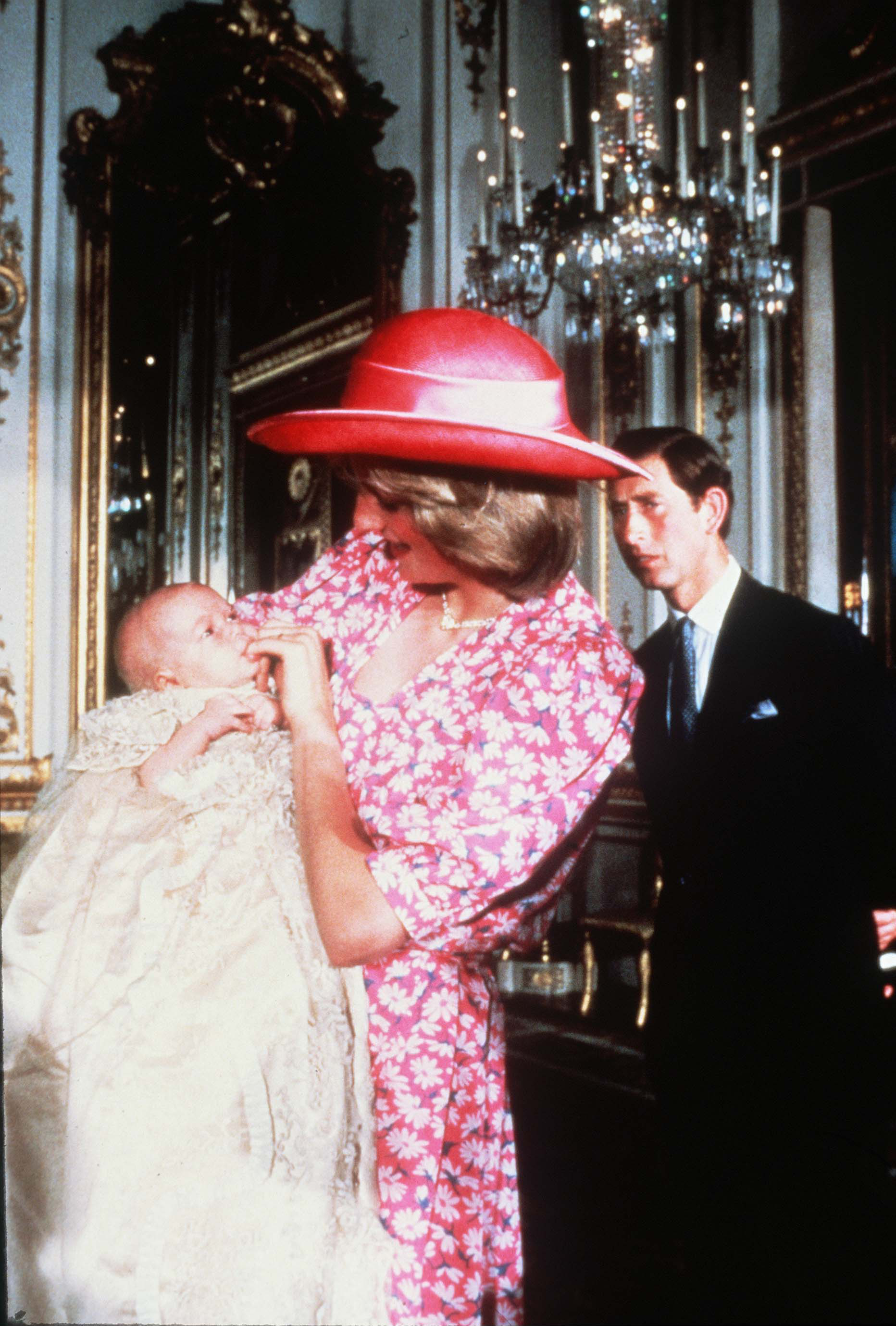 Princess Diana wears a pink floral dress and pink hat to hold Prince William on August 4, 1982 at his royal christening