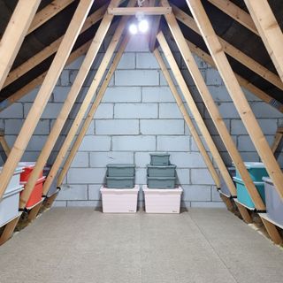 Attic with organised storage boxes on floor beneath bright 3-way light