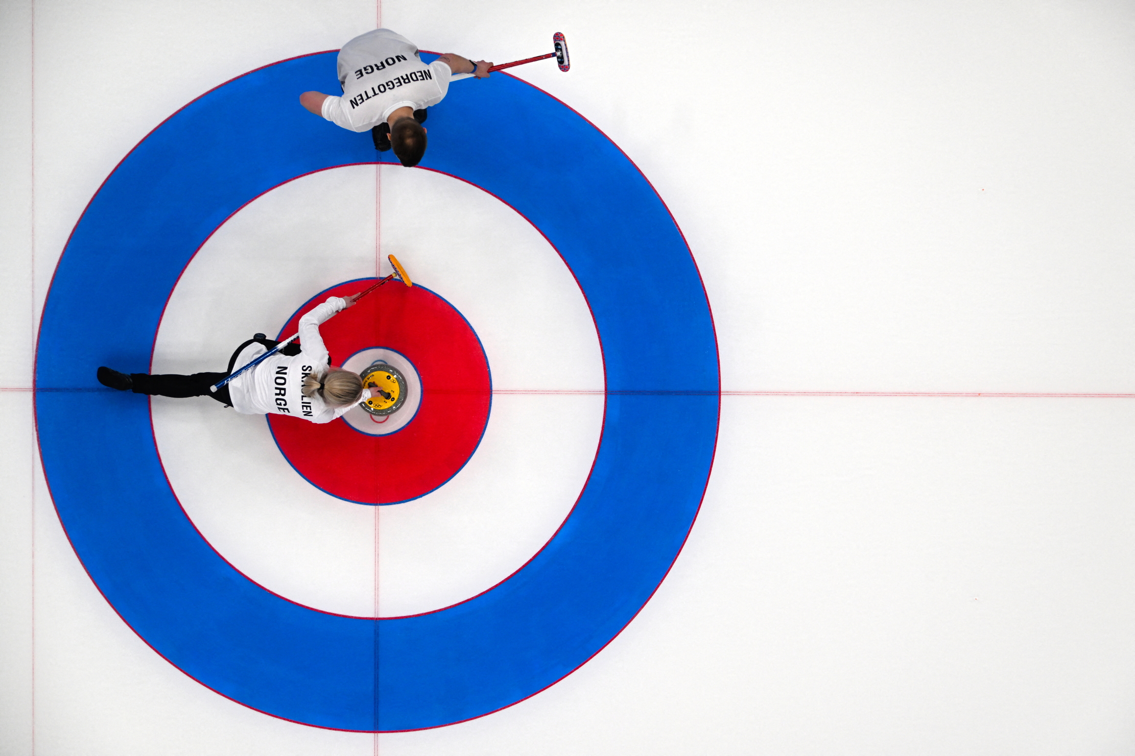 Norway&rsquo;s Kristin Skaslien (C) curls the stone as Norway&rsquo;s Magnus Nedregotten prepares to sweep during the mixed doubles gold medal game of the Beijing 2022 Winter Olympic Games curling competition between Italy and Norway at the National Aquatics Centre in Beijing on February 8, 2022