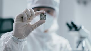Semiconductor worker holding a wafer chip.