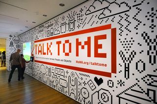 Pixel art: Two people look at "Talk to me" mural at MoMA