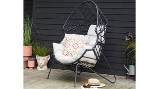 Black pod chair with beige cushion on backyard patio ; best outdoor furniture