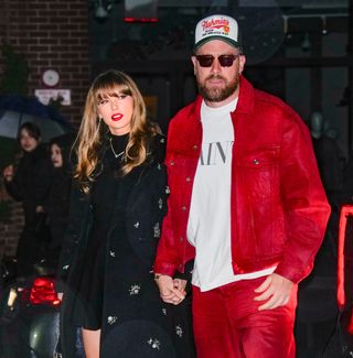 Taylor Swift in a black dress and black coat and Travis Kelce in red pants, a red jacket, and white T-shirt with a cap and sunglasses in New York City in December 2024