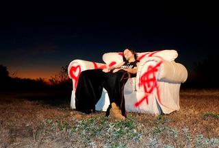 Musician Morgan Saint takes us behind-the-scenes of her "Kiss" video sitting in an oversize spray-painted white chair outside.