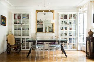 A French apartment features mid-century modern and modern glamorous furniture including spherical lighting, resin chairs, and rattan accents.