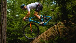 A white man rides down a steep rock slab on a bike with orange suspension forks