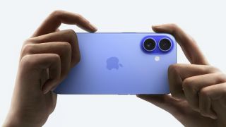 A person holding up a blue iPhone 16 to take a photo