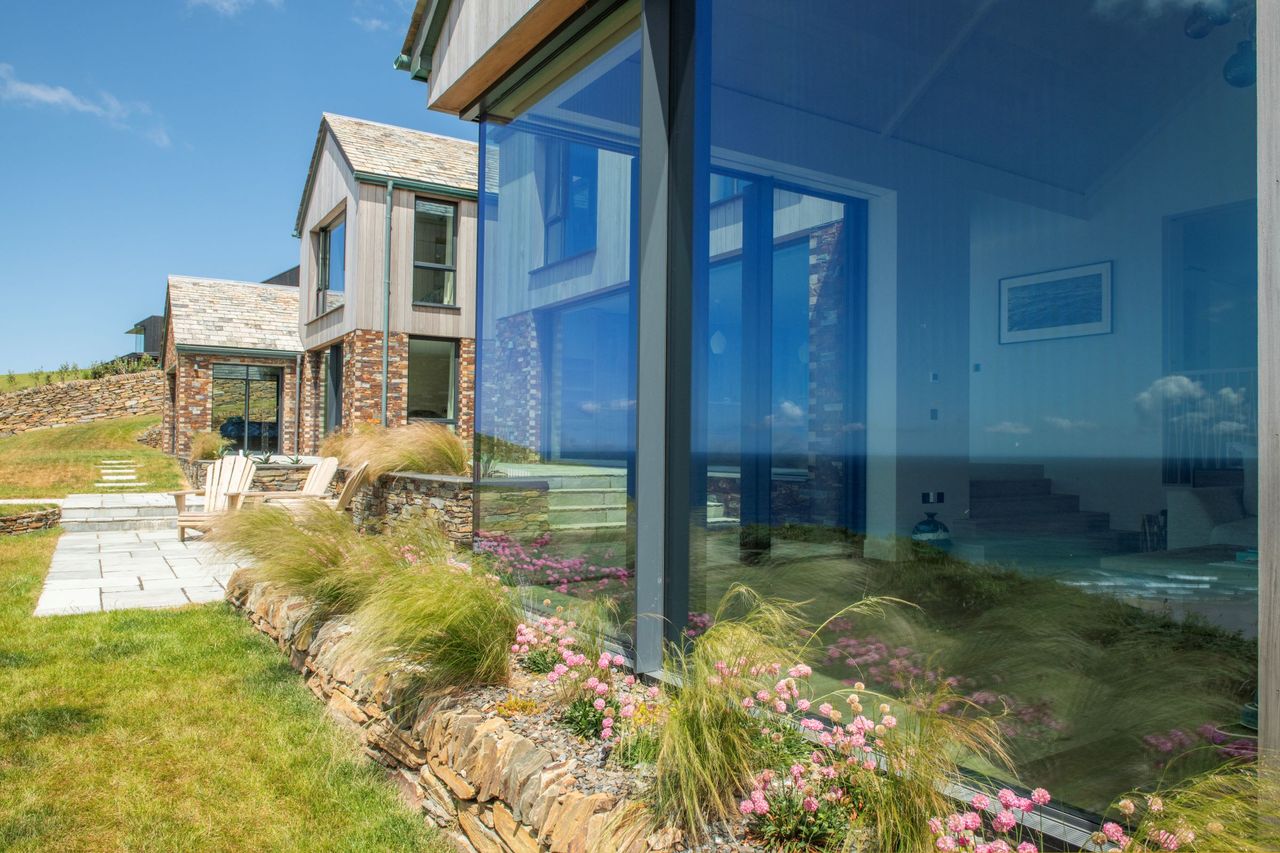 A large bifold window with plants on the exterior facing the sea