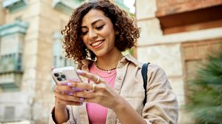 woman outside in a pink top using phone