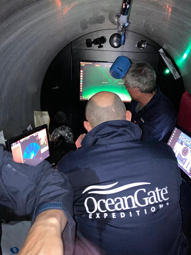 Five crew are packed tightly into a cylindrical submersible.