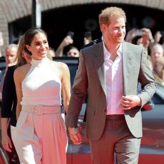 Meghan Markle and Prince Harry enter the invictus games in beige outfits including a white tank top and belted khaki pants