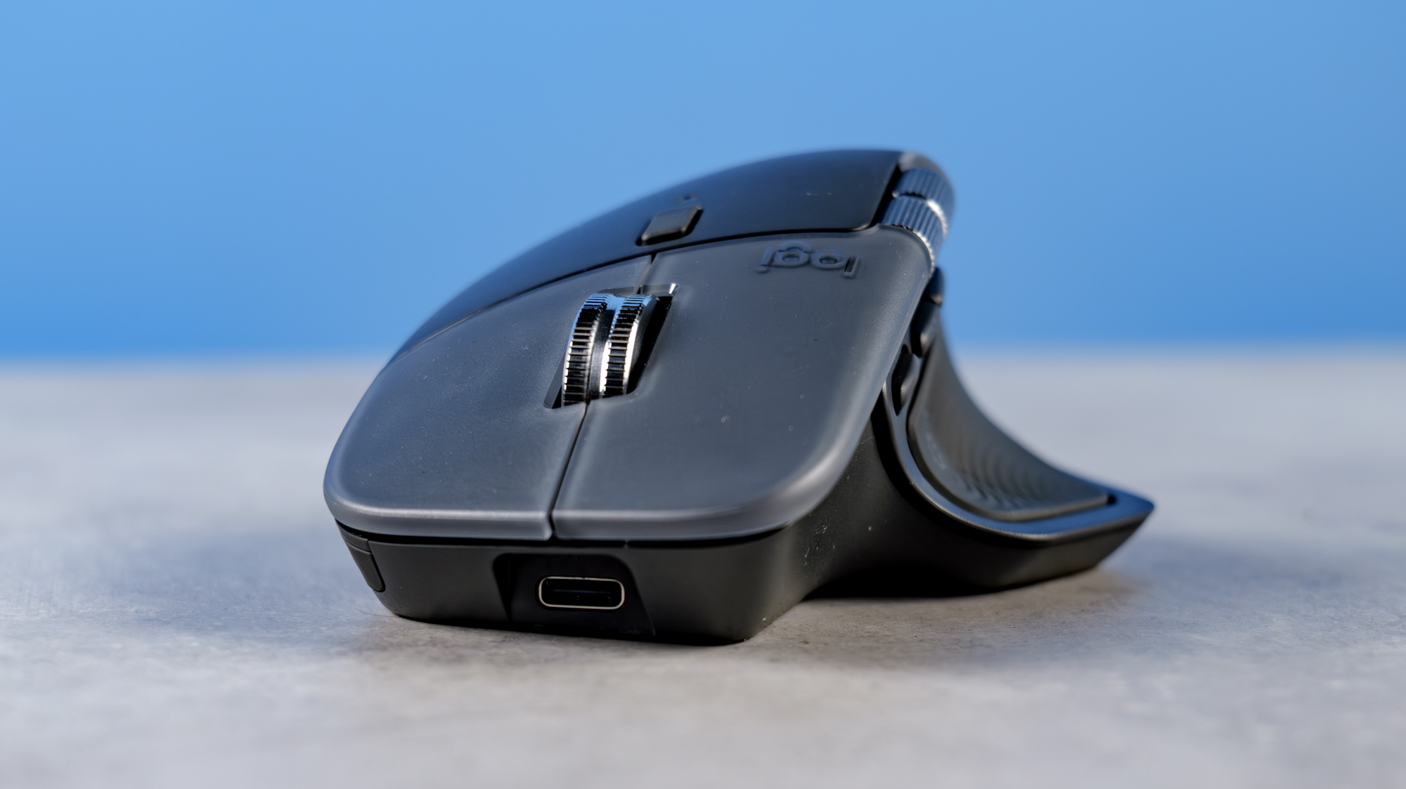 A photo of the Logitech MX Master 4 on a stone surface with a blue background