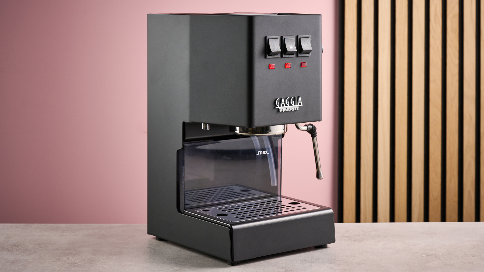The Gaggia Classic E24 Evo Pro in front of a pink background with a slatted wooden panel.