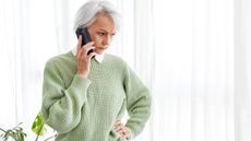 An older woman looks concerned as she talks on the phone.