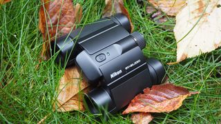 Nikon Stabilized 12x25 S binoculars on grass surrounded by brown leaves