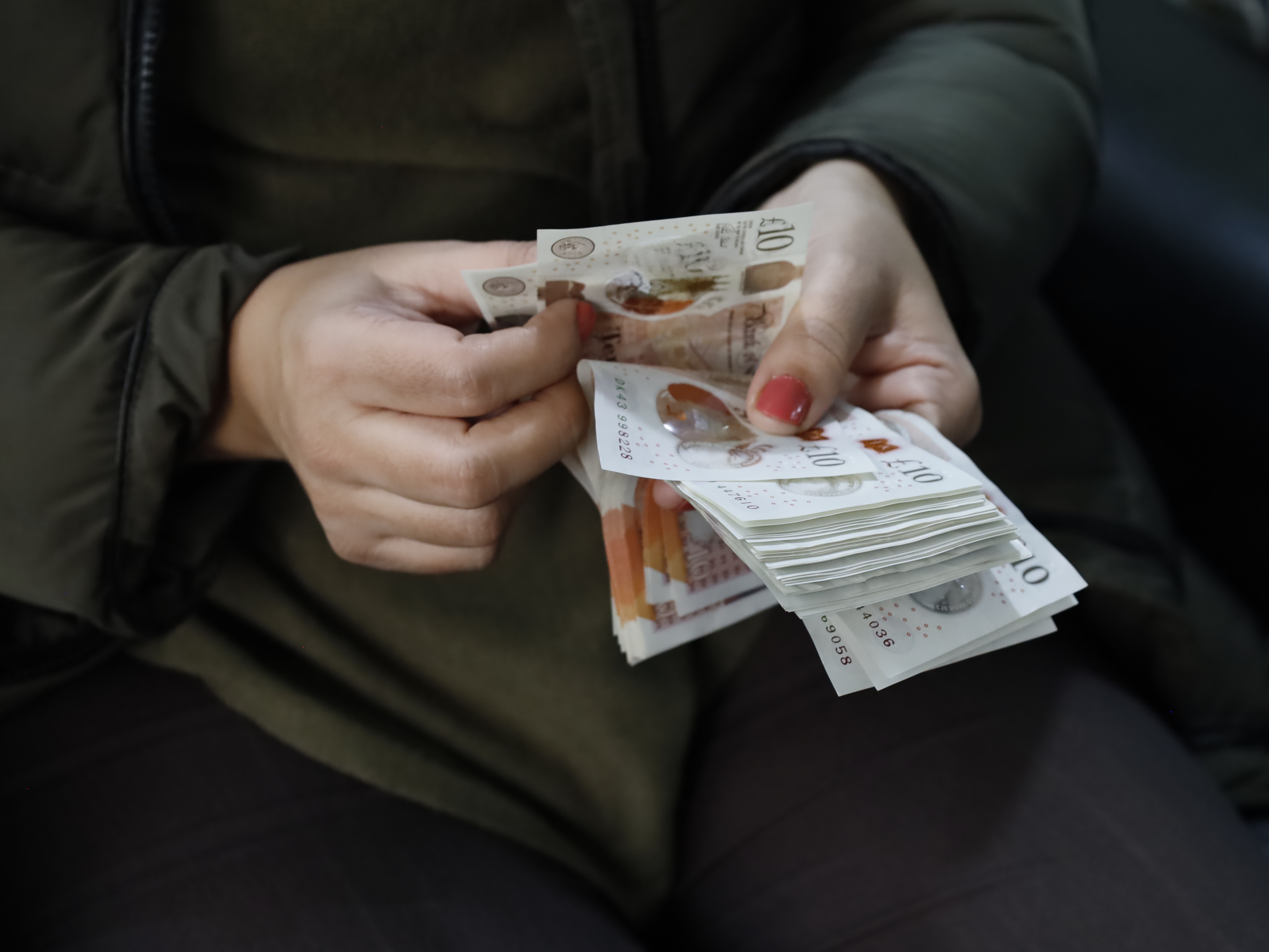 Person holds wad of bank notes after receiving windfall.