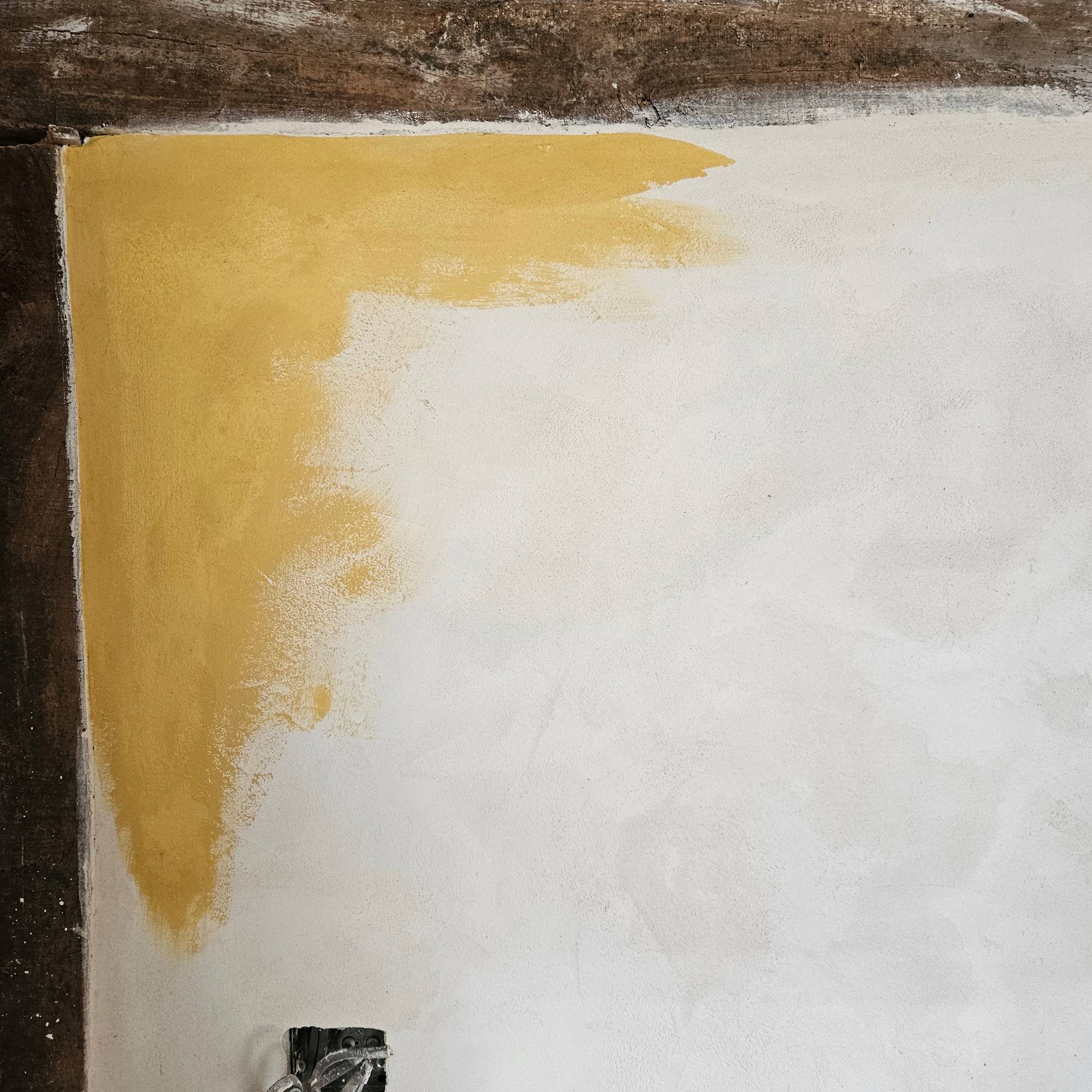 white lime plastered wall painted with yellow