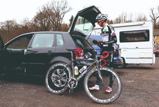 A road racer stands next to his car with the boot open